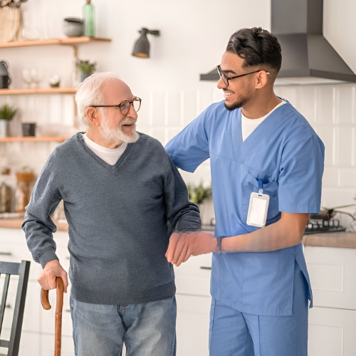A professional home care worker assisting an elderly man with mobility support at home, providing compassionate aged care and daily living assistance.