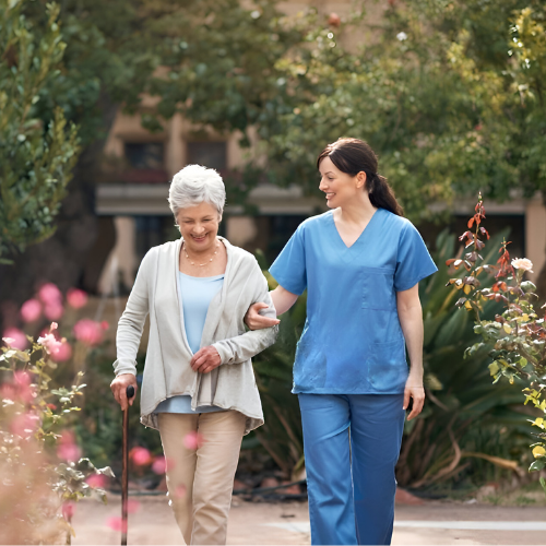 A friendly aged care nurse walking with an elderly woman outdoors, offering personalised home care support and companionship for seniors.