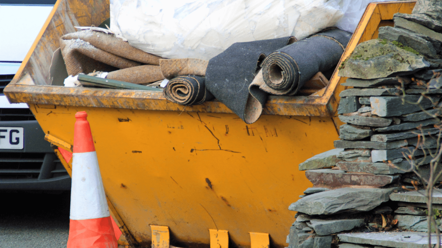 Large yellow waste skip filled with garden and home renovation rubbish